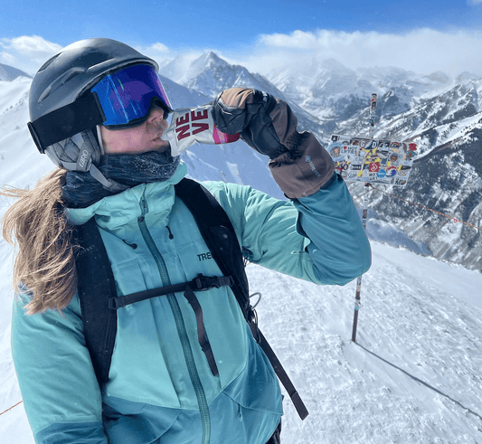 Skier uses Neve Boysenberry Beet Smoothie Pouch while skiing 
