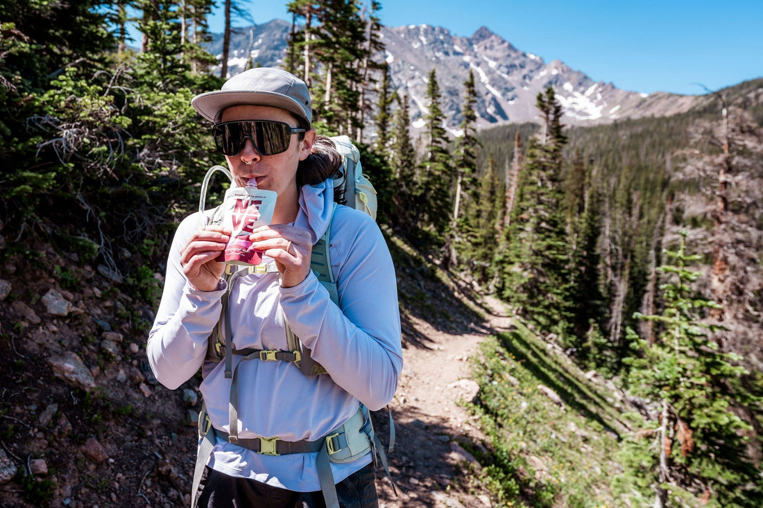 Hiker uses Neve Boysenberry Beet Smoothie Pouch for sustained energy during a hike.