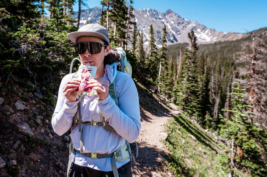 Hiker uses Neve Boysenberry Beet Smoothie Pouch for sustained energy during a hike.