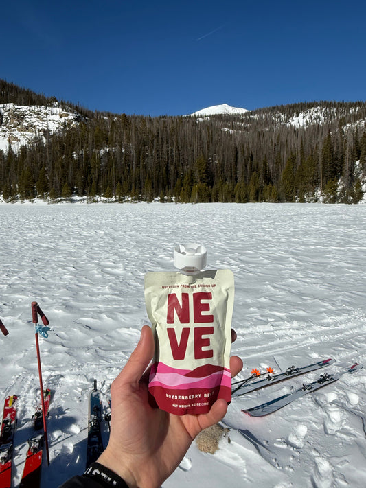 Boysenberry Beet Neve Energy Smoothie Pouch held up with snowy background 