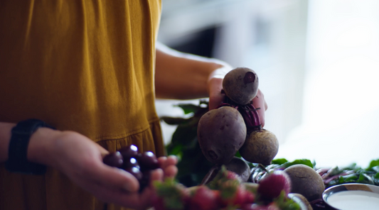 Holding cherries in one hand and beets in the other, the ingredients for Neve's Boysenberry Beet Smoothie Pouch