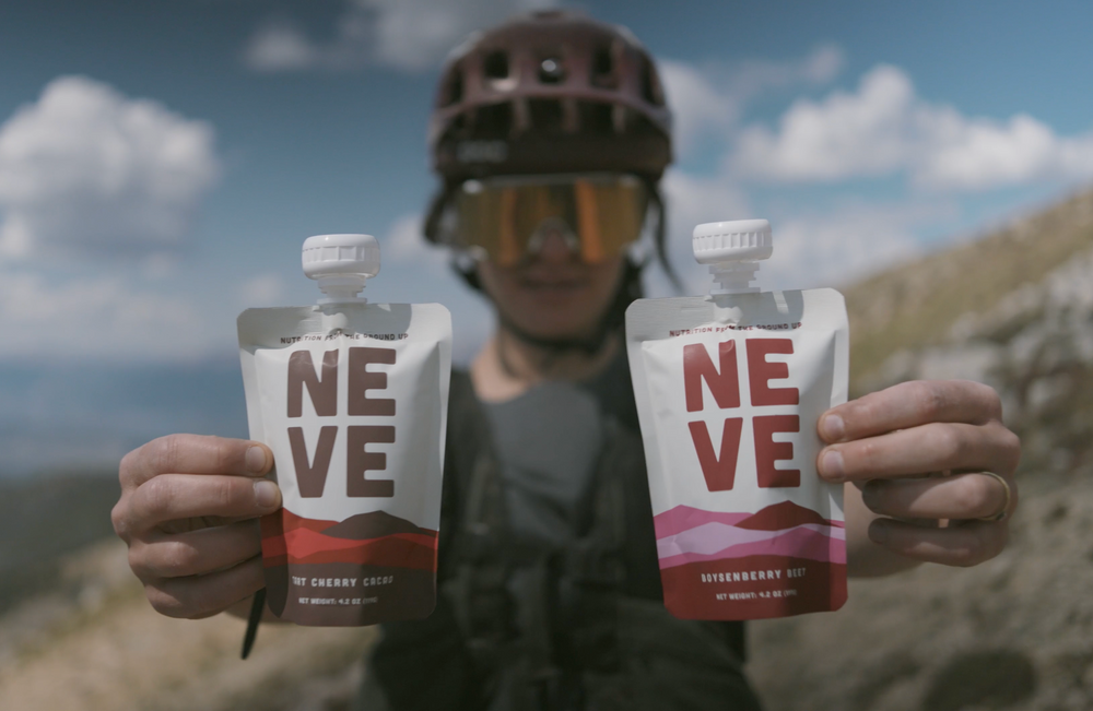 Two Neve Smoothie Pouches - Boysenberry Beet and Tart Cherry Cacao - held up by mountain biker.