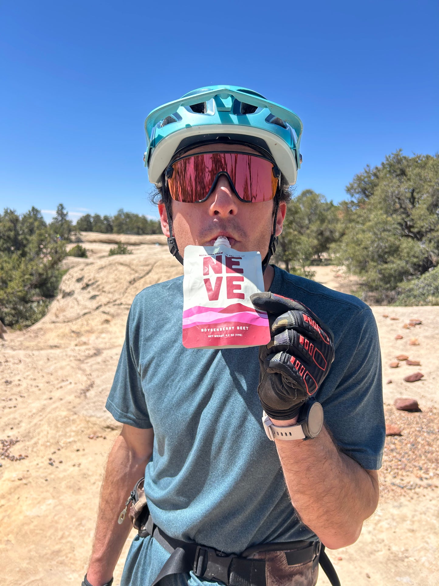 Mountain biker using Neve's Boysenberry Beet Energy smoothie pouch in the desert 