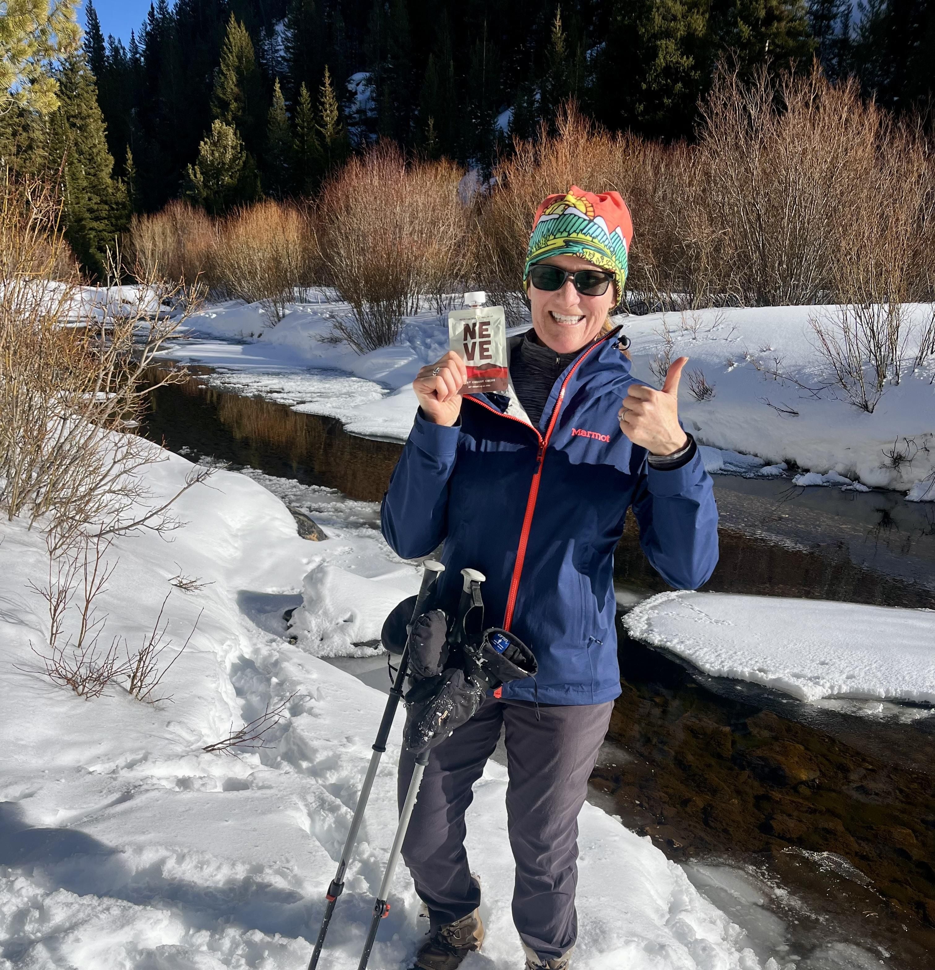 Tart Cherry Cacao recovery smoothie pouch held up by hiker in the winter